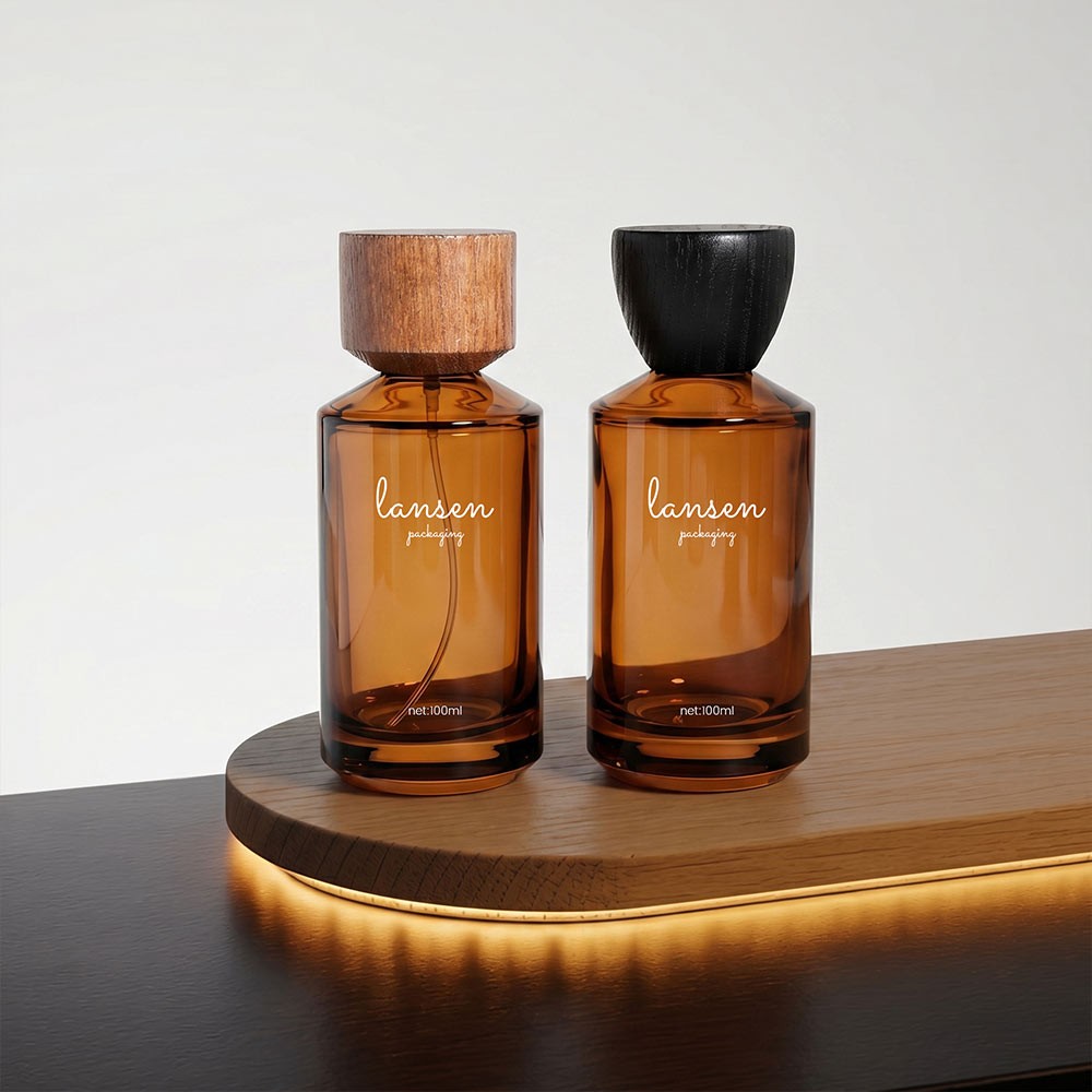 a pair of 100ml amber cylinder glass perfume bottles with walnut and black wood caps on a wooden tray