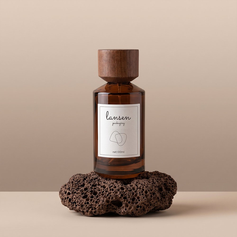 100ml amber cylinder glass perfume bottle with a light walnut wooden cap standing on a dark porous rock