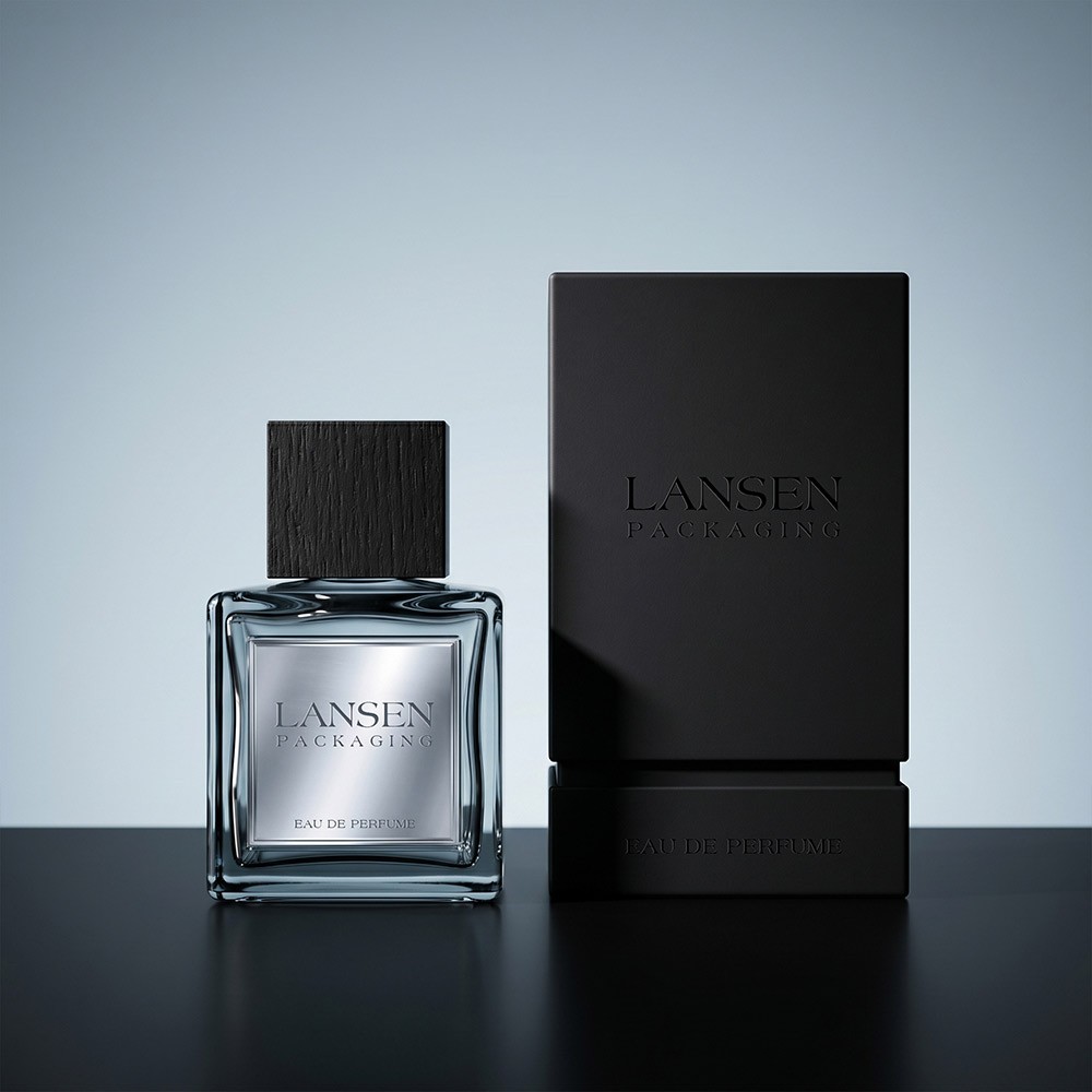 100ml square glass perfume bottle with a brushed silver metal label standing next to its matte black rigid box