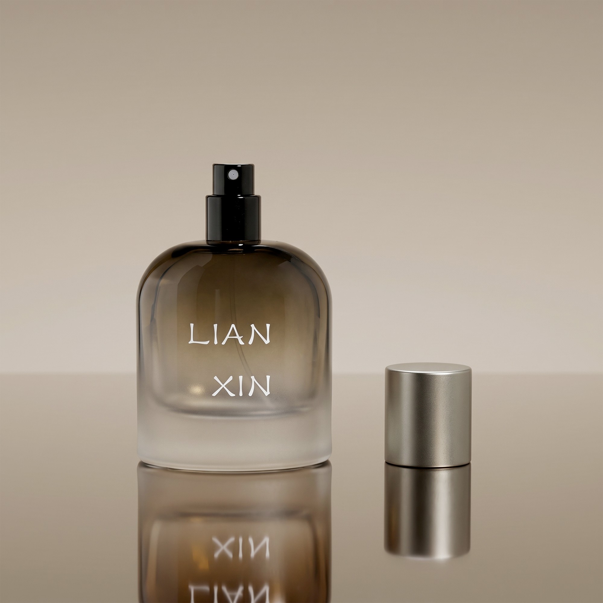 50ml barrel shaped perfume bottle with the black sprayer exposed and the brushed silver cap standing beside it