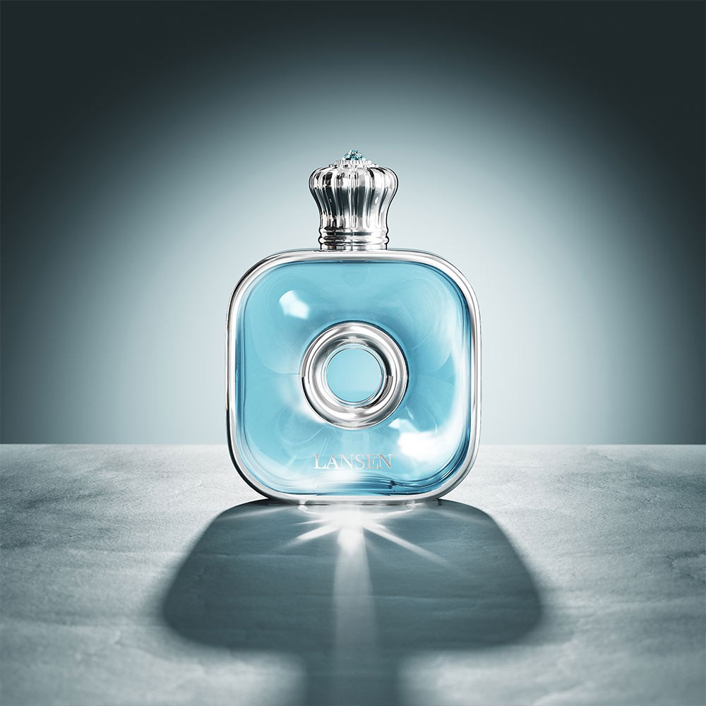 light blue 50ml flat square perfume bottle with a silver crown shaped cap and a circular ring on the front panel, lit against a dark grey background