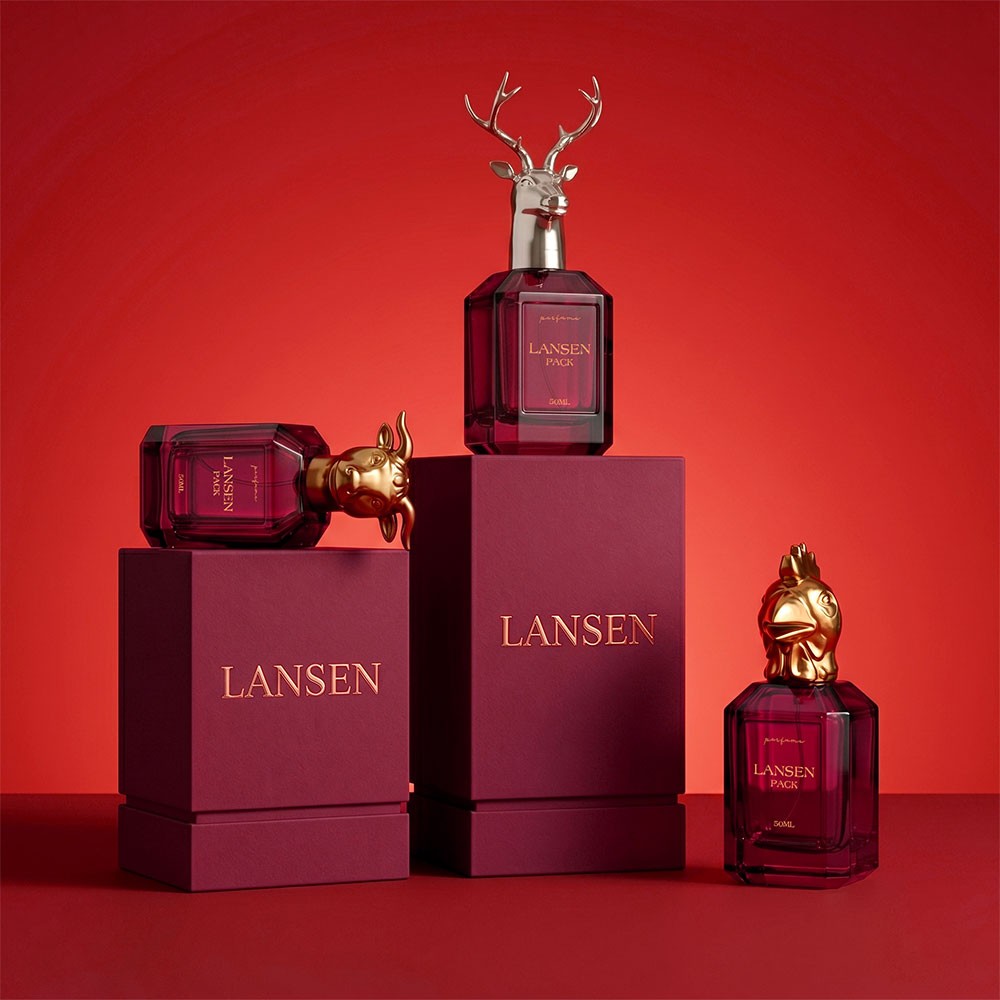 three 50ml rectangular perfume bottles with gold and silver animal head caps standing on maroon gift boxes