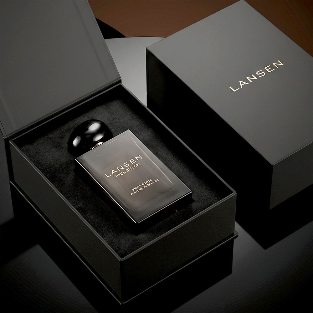50ml smoky brown perfume bottle lying in the black flocked foam insert of an open matte black gift box with its lid beside it