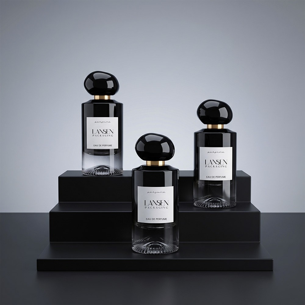 three black gradient glass perfume bottles of different heights with spherical caps displayed on black plinths