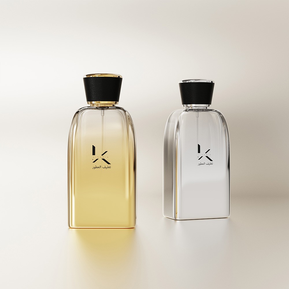 amber gold and mirrored silver sloped shoulder perfume bottles with black leather covered caps on a soft grey background