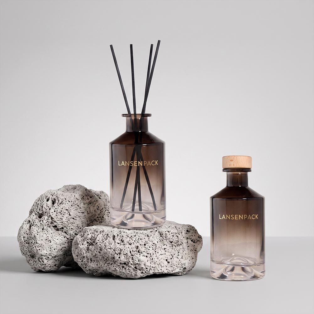 200ml smoky brown gradient glass reed diffuser bottle with black reeds beside a matching capped bottle