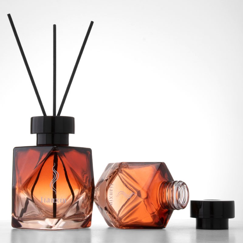 irregular faceted amber glass reed diffuser bottle with black reeds and separate black screw cap