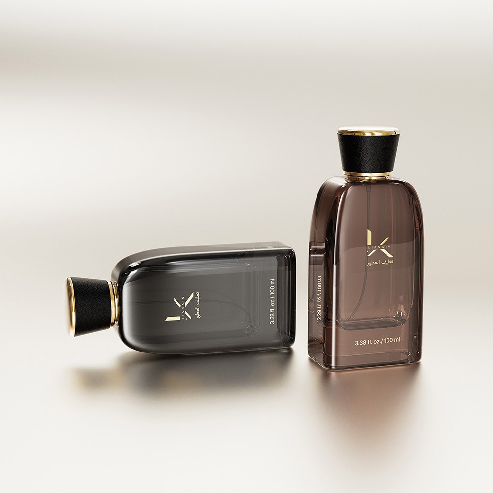 smoke glass and mirrored silver perfume bottles with black leather covered caps, one standing and one lying on a soft grey background